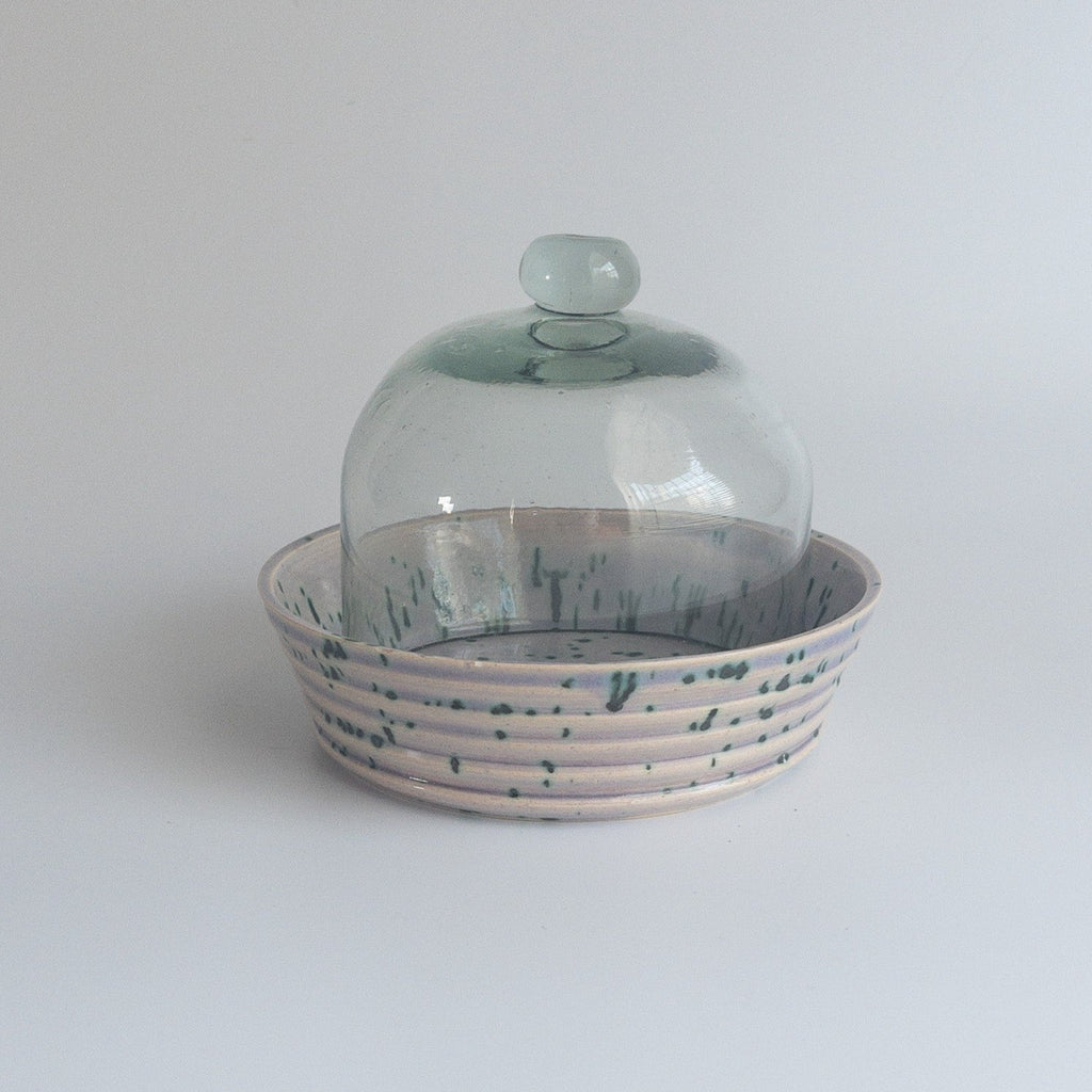 Studio CM | a speckled pink, purple and green handmade ceramic plate with a glass cloche over it