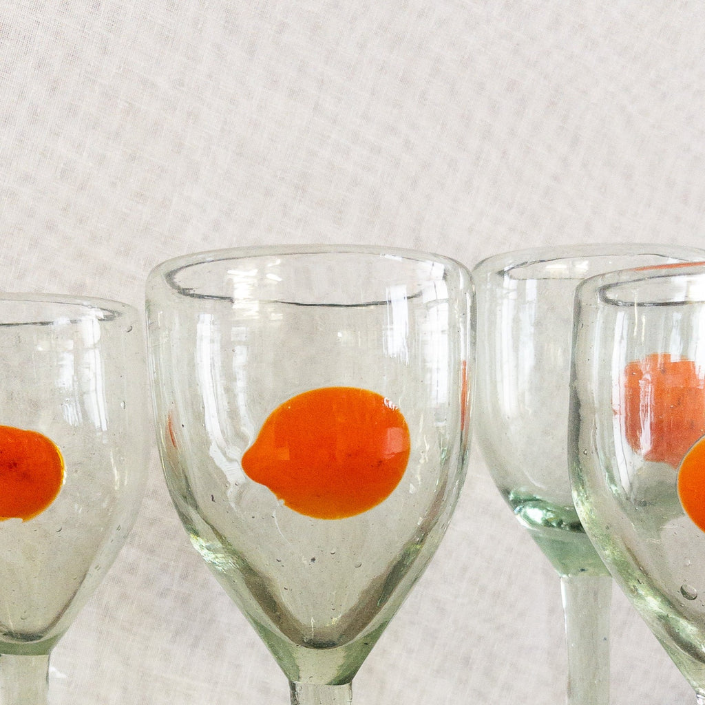 Studio CM | A stemmed glass hand blown from recycled glass that has an orange dot design made in Mexico