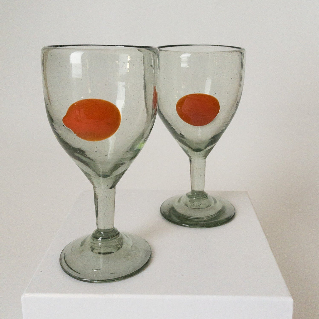 Studio CM | A stemmed glass hand blown from recycled glass that has an orange dot design made in Mexico