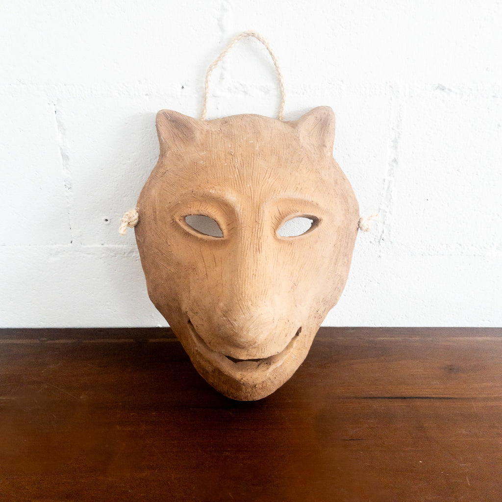 Studio CM | A ceramic mask in the shape of a wolf face made in terracotta colored clay with a role for mounting. Made in Oaxaca, Mexico. 