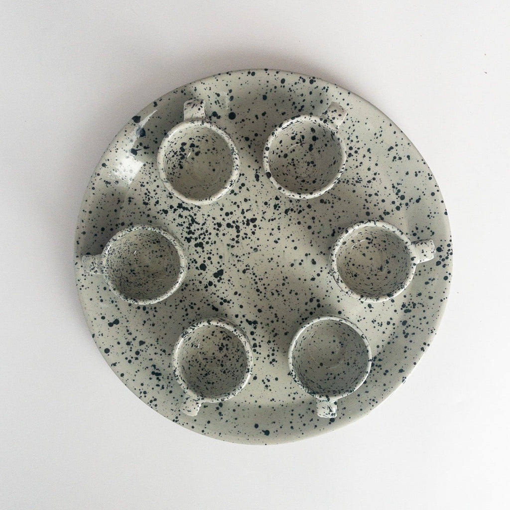 Studio CM | a ceramic plate that is gray and speckled blue with its set of 6 mugs made in Michoacan Mexico