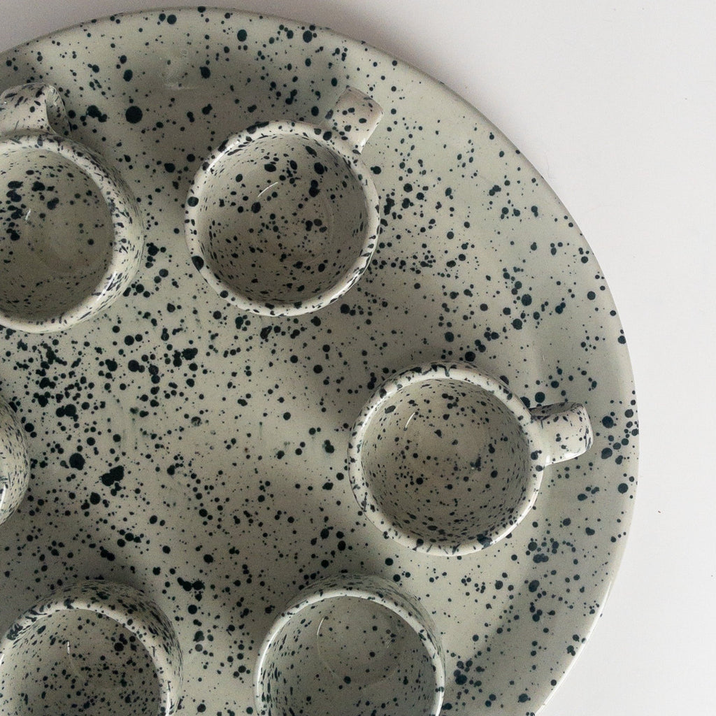 Studio CM | a ceramic plate that is gray and speckled blue with its set of 6 mugs made in Michoacan Mexico