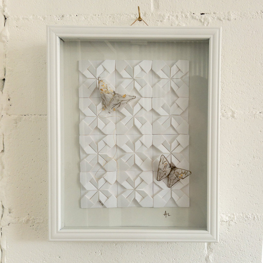 Studio CM | A framed composition made of origami. It's a wall decor piece by Alicia Lopez with white origami squares and butterflies. 