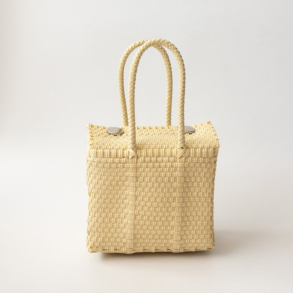 Studio CM | A hand woven cream plastic reusable purse. It is woven together with individual strands, held together by magnetic buttons and has two straps.