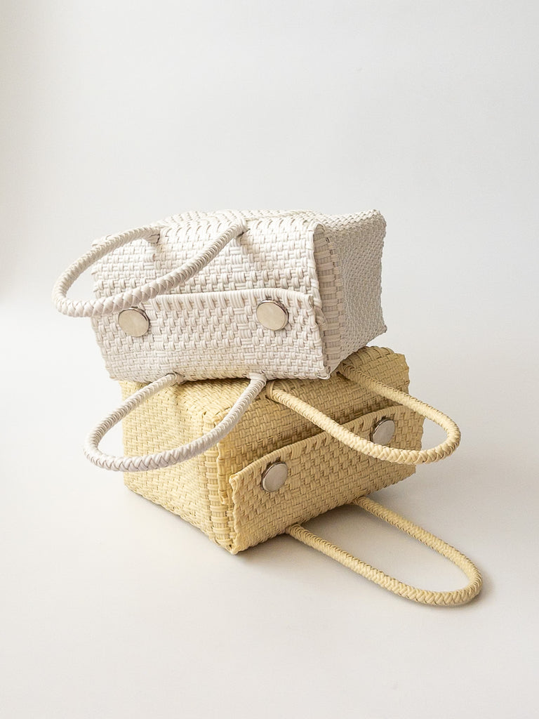 Studio CM | Two reusable plastic purses that are stacked on each other in cream and white with straps and magnetic buttons