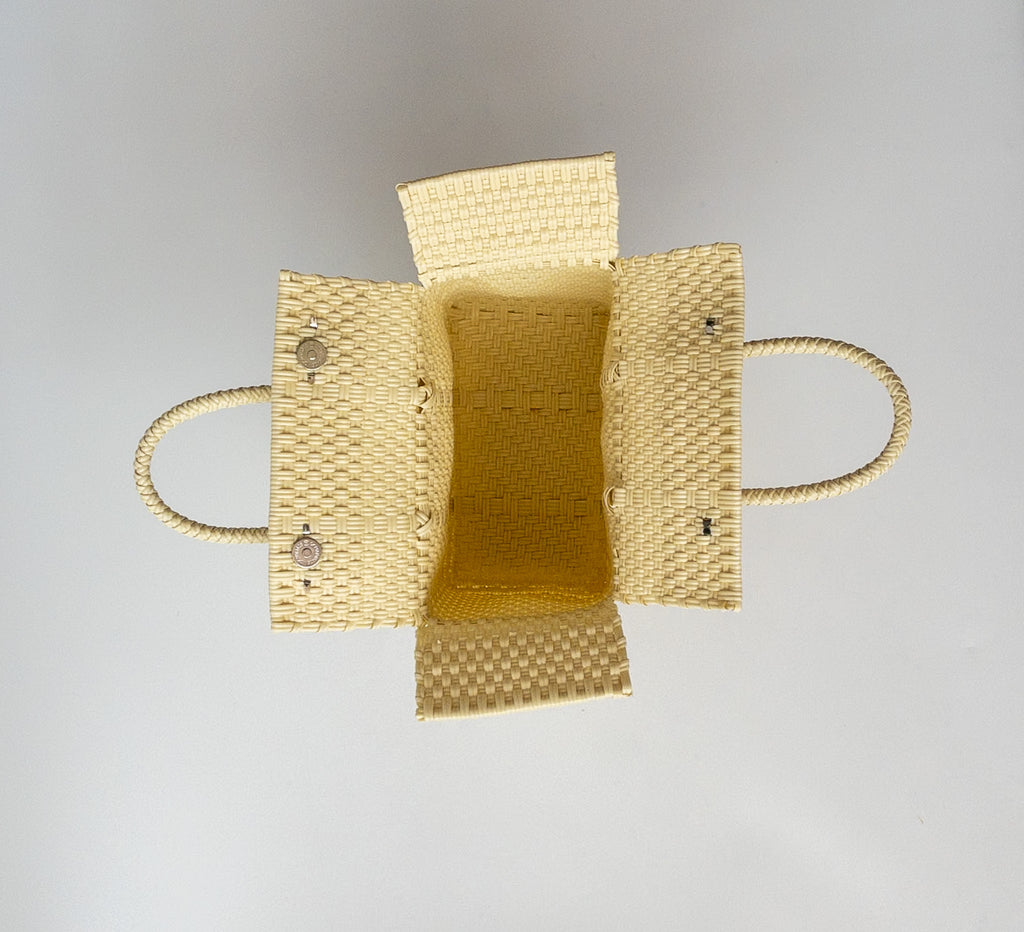 Studio CM | A hand woven cream plastic reusable purse. It is woven together with individual strands, held together by magnetic buttons and has two straps.