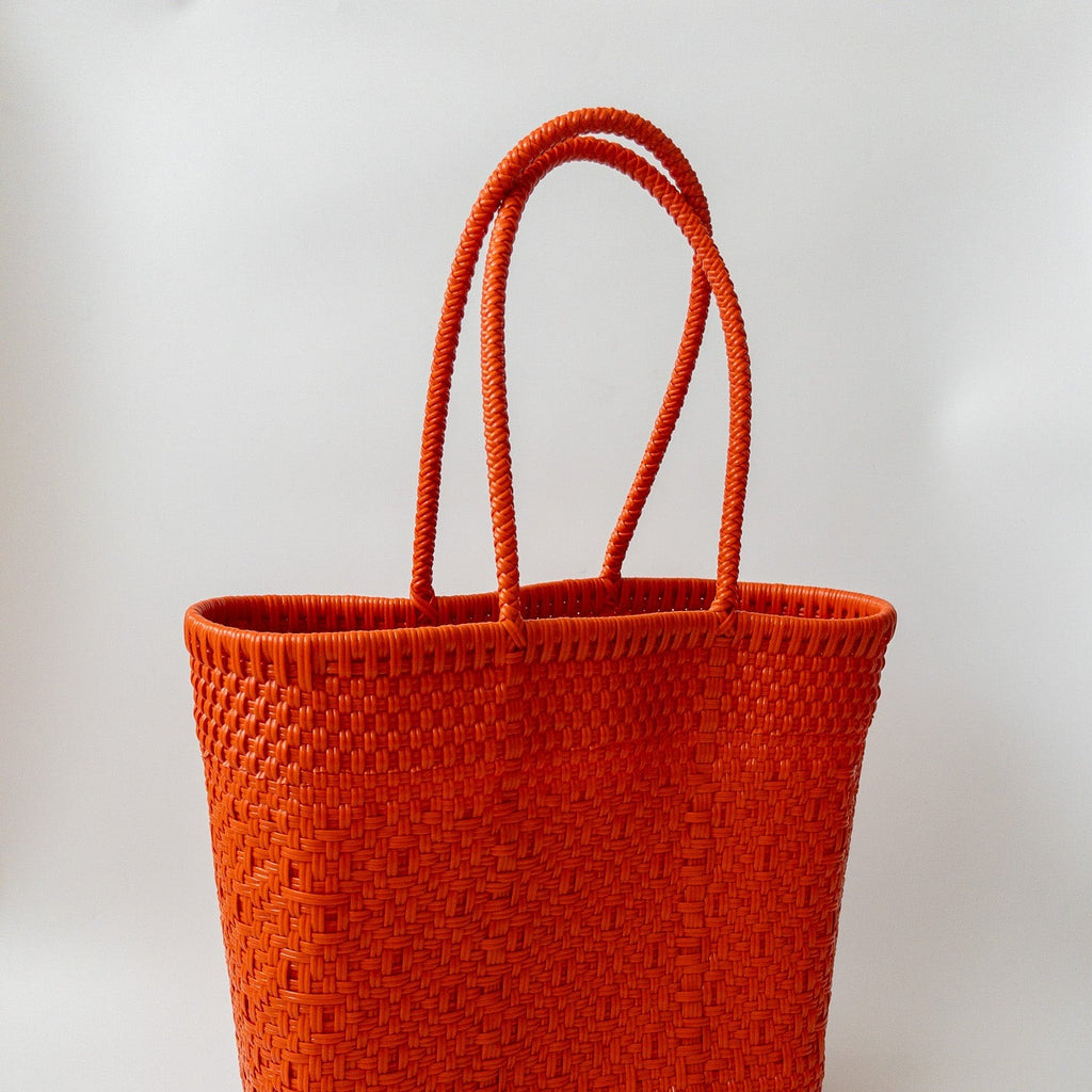 Studio CM | A handmade purse from Jalisco, MX that is woven by orange plastic strands. It is a large tote that can be used for the beach or travel due to being highly resistant.