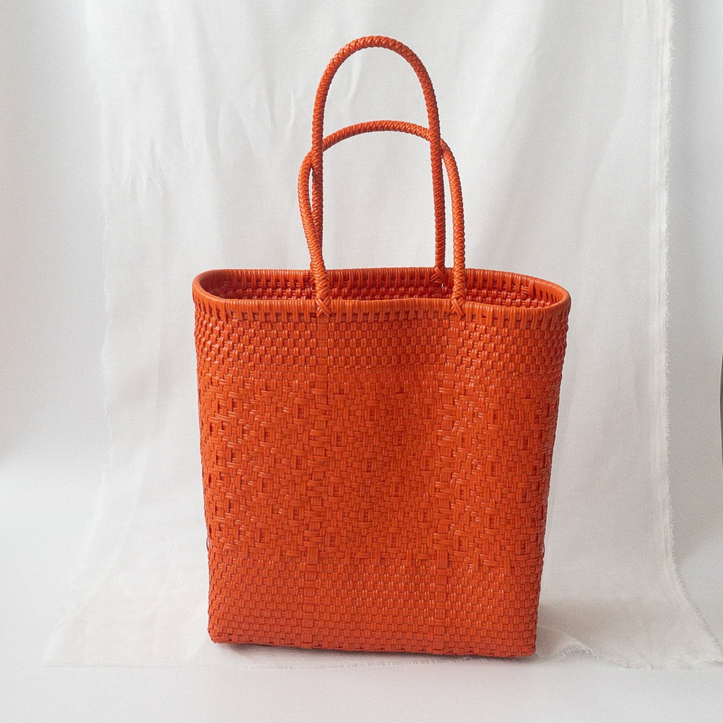 Studio CM | A handmade purse from Jalisco, MX that is woven by orange plastic strands. It is a large tote that can be used for the beach or travel due to being highly resistant. 