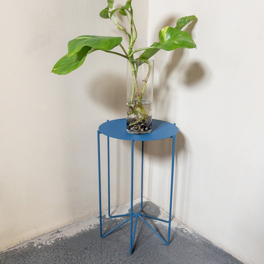 Studio CM | A modern metal table that has a beautiful blue finish decorated with a vase and greenery. Table made in Guadalajara, Mexico.