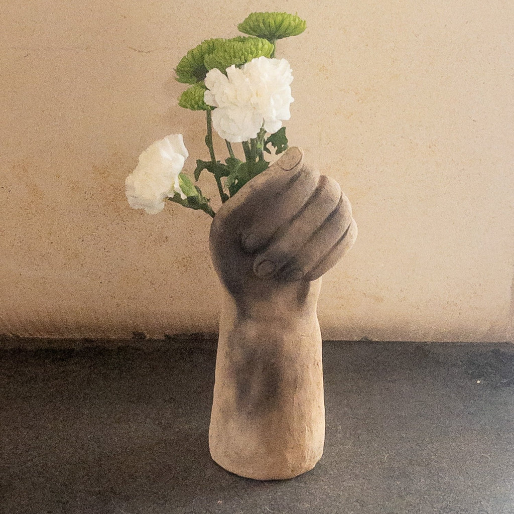 Studio CM | a sculpture that serves as a vase hand made from ceramic that is in the shape of a hand grasping flowers