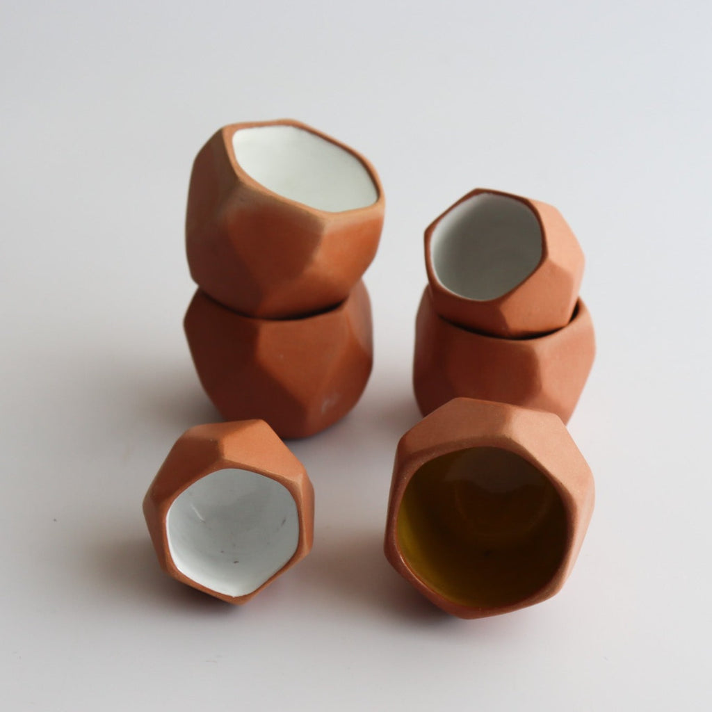 six geometric shot glasses made of ceramic with an interior white glaze