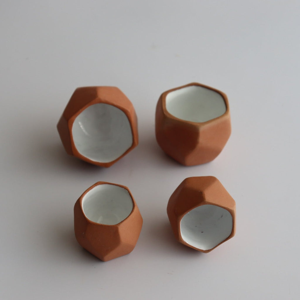 four  geometric shot glasses made of ceramic with an interior white glaze