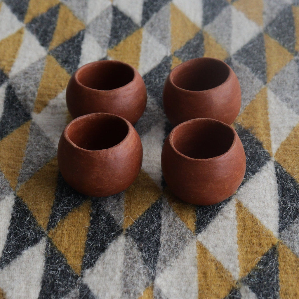 Studio CM | four red ceramic round shot glasses with a geometric background