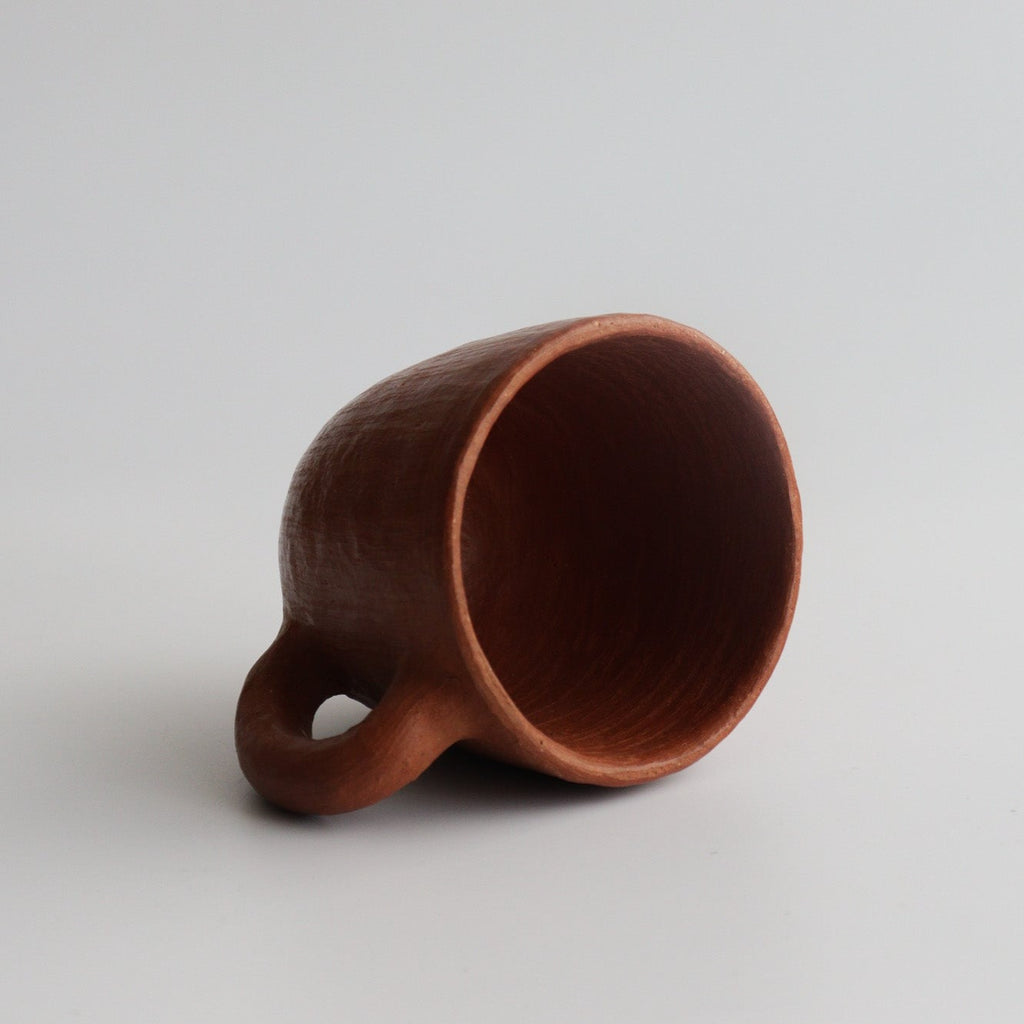 Studio CM | red ceramic mug tipped over with  a white background