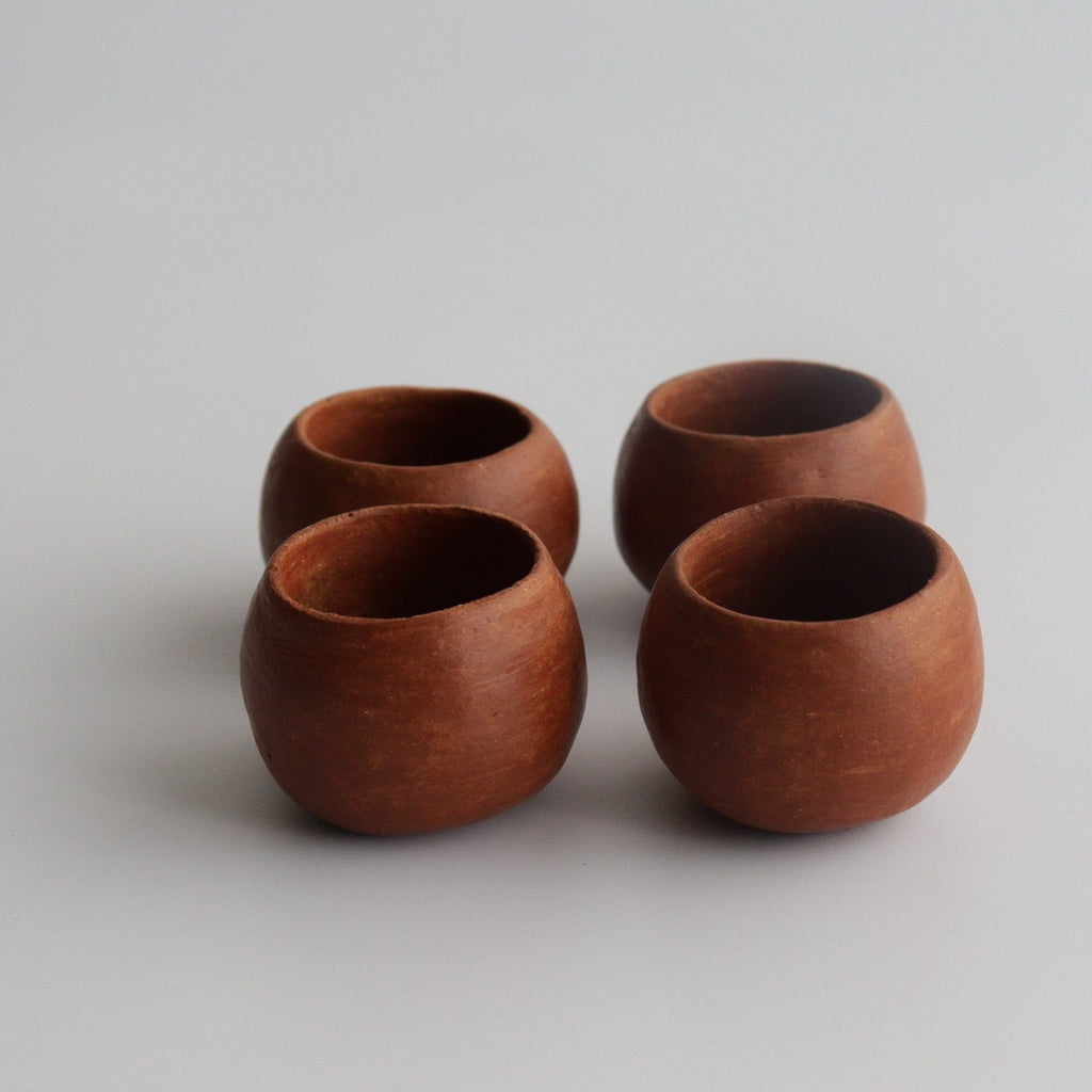 Studio CM | four red ceramic round shot glasses with a white background