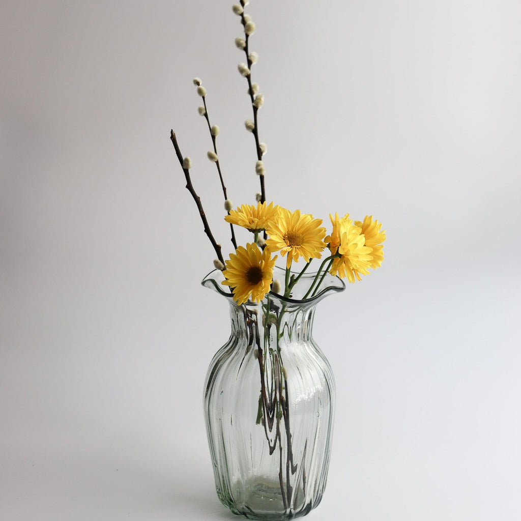 Studio CM | a handblown clear vase with a wavy abstract mouth shape decorated with yellow daisies