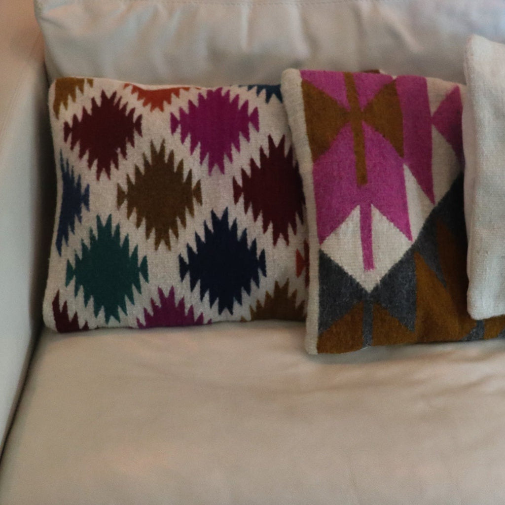 two different zapotec pillows handmade in oaxaca with natural dyes and materials placed on a cream leather couch