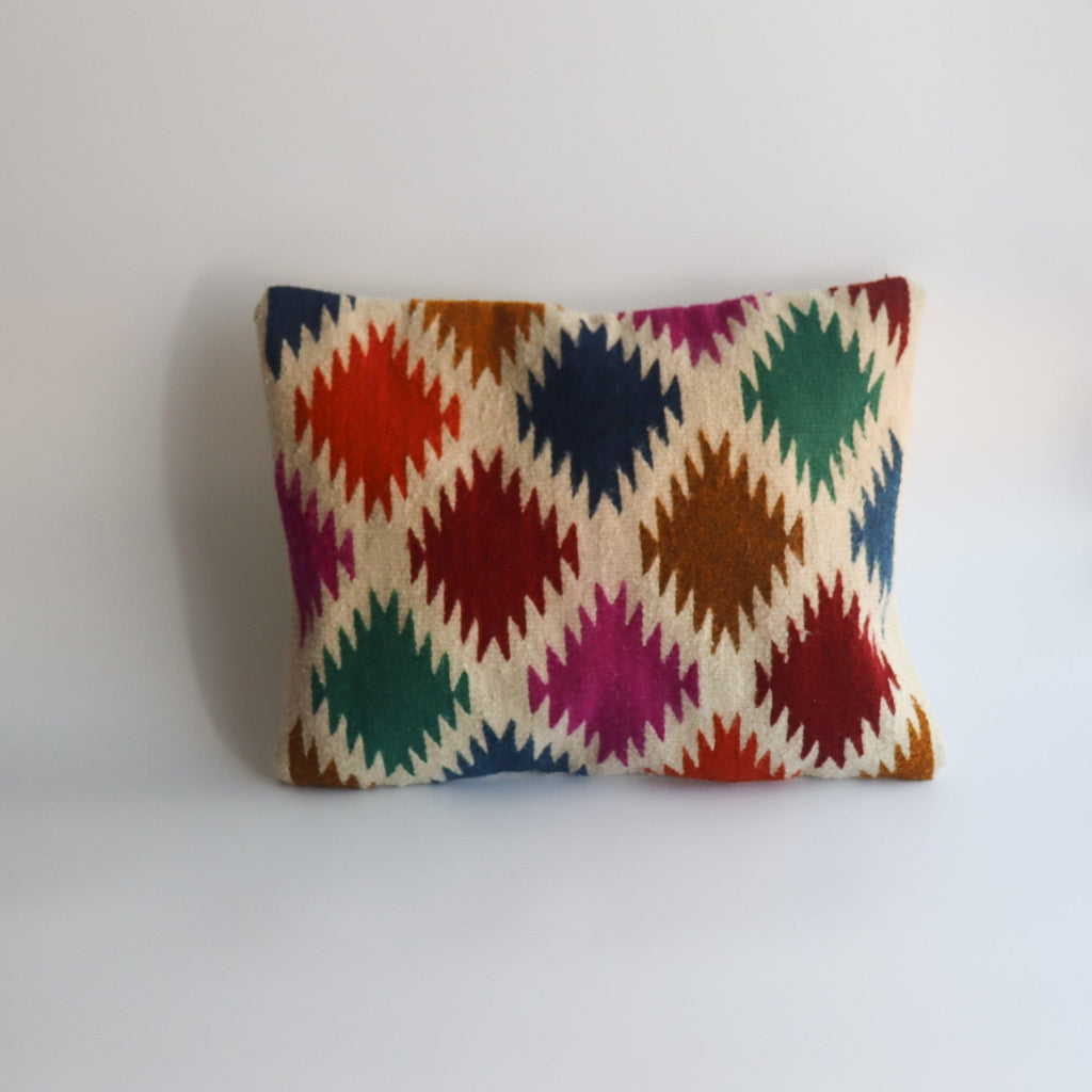 multicolored abstract diamond shaped shapes on a pillow that is handmade in oaxaca from organic materials