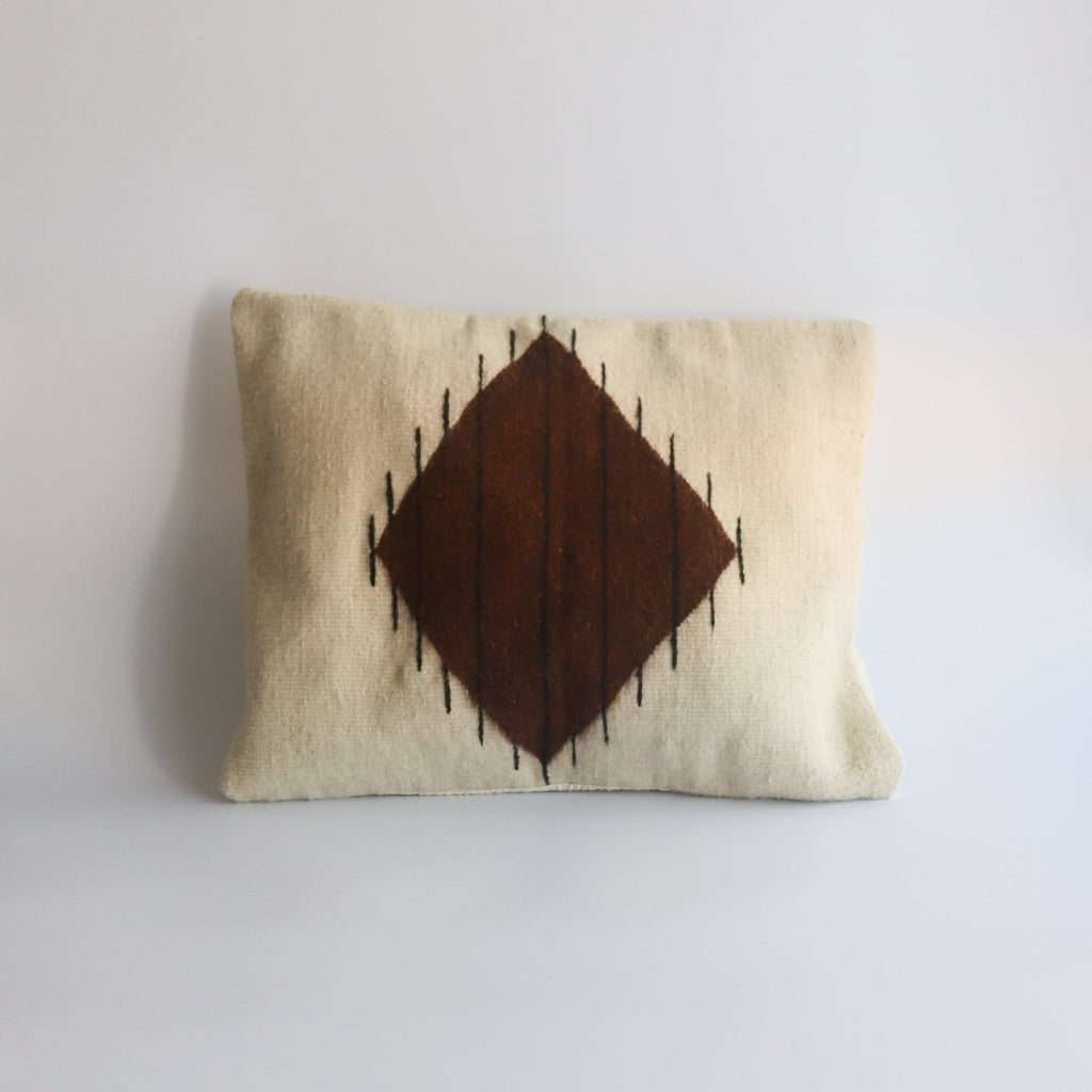 handwoven pillowcase made from organic wool and natural dyes with a brown diamond shape and black thin lined on a white canvas