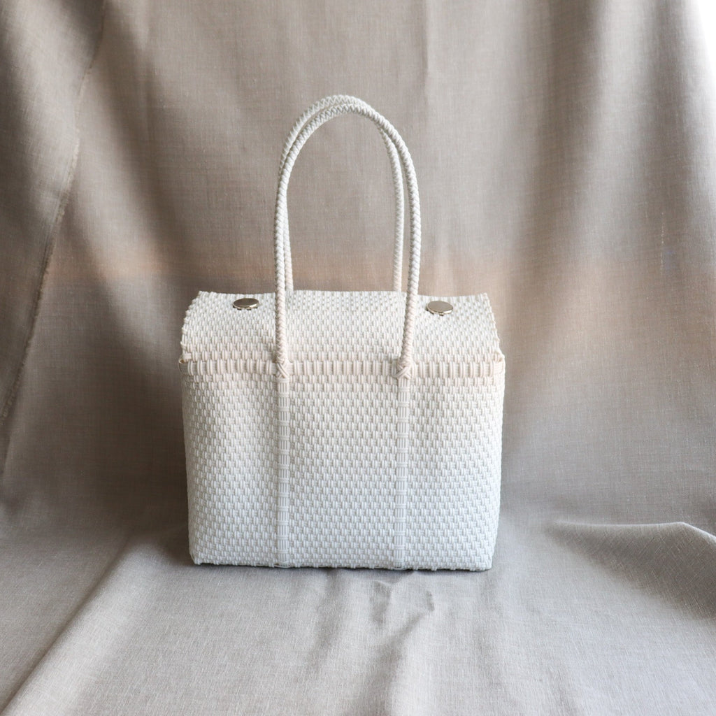 Studio CM | A hand woven white plastic reusable purse. It is woven together with individual strands, held together by magnetic buttons and has two straps.