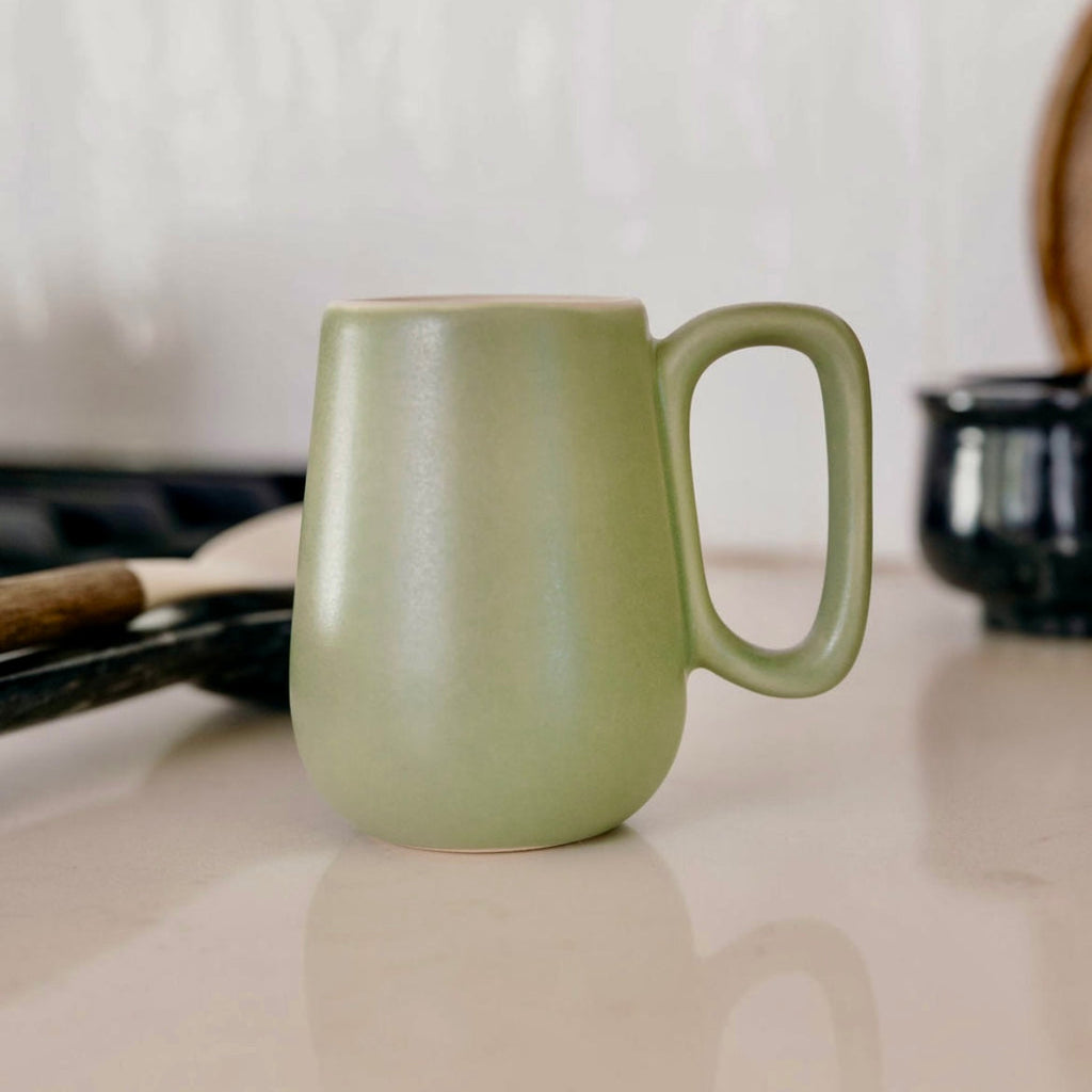 Studio CM | Green ceramic mug on a kitchen counter with a blurred background