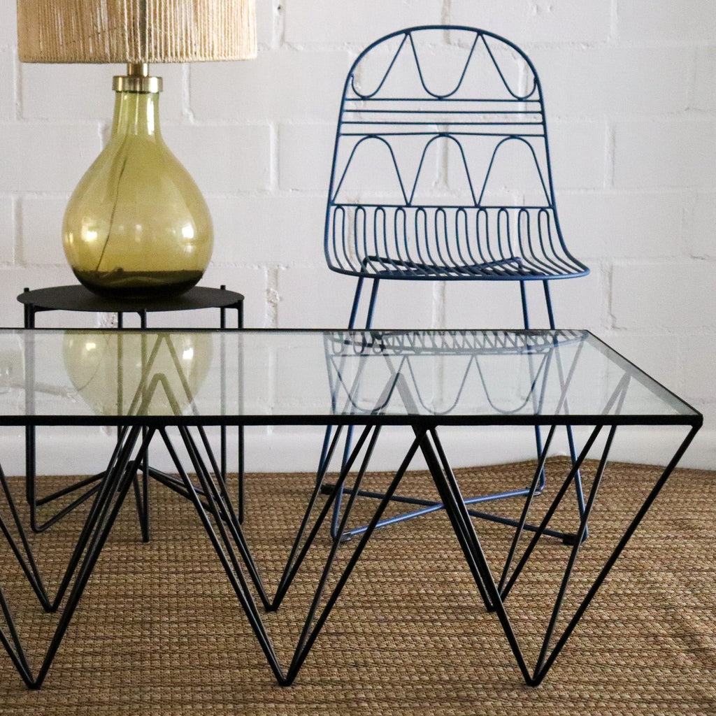 Studio CM | a modern rod iron coffee table that is made with metal triangular legs and a tempered glass top to size. The product is welded in Guadalajara Mexico