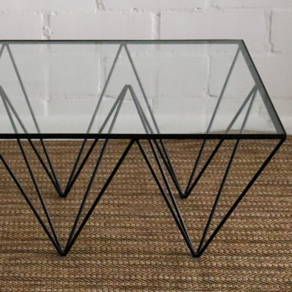 Studio CM | a modern rod iron coffee table that is made with metal triangular legs and a tempered glass top to size. The product is welded in Guadalajara Mexico