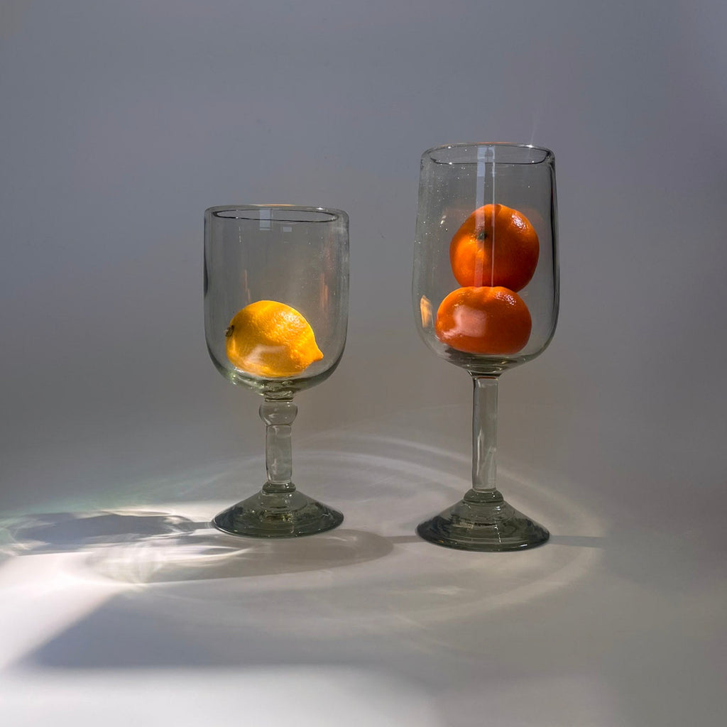 Studio CM | Two glass goblets with oranges inside on a gray background