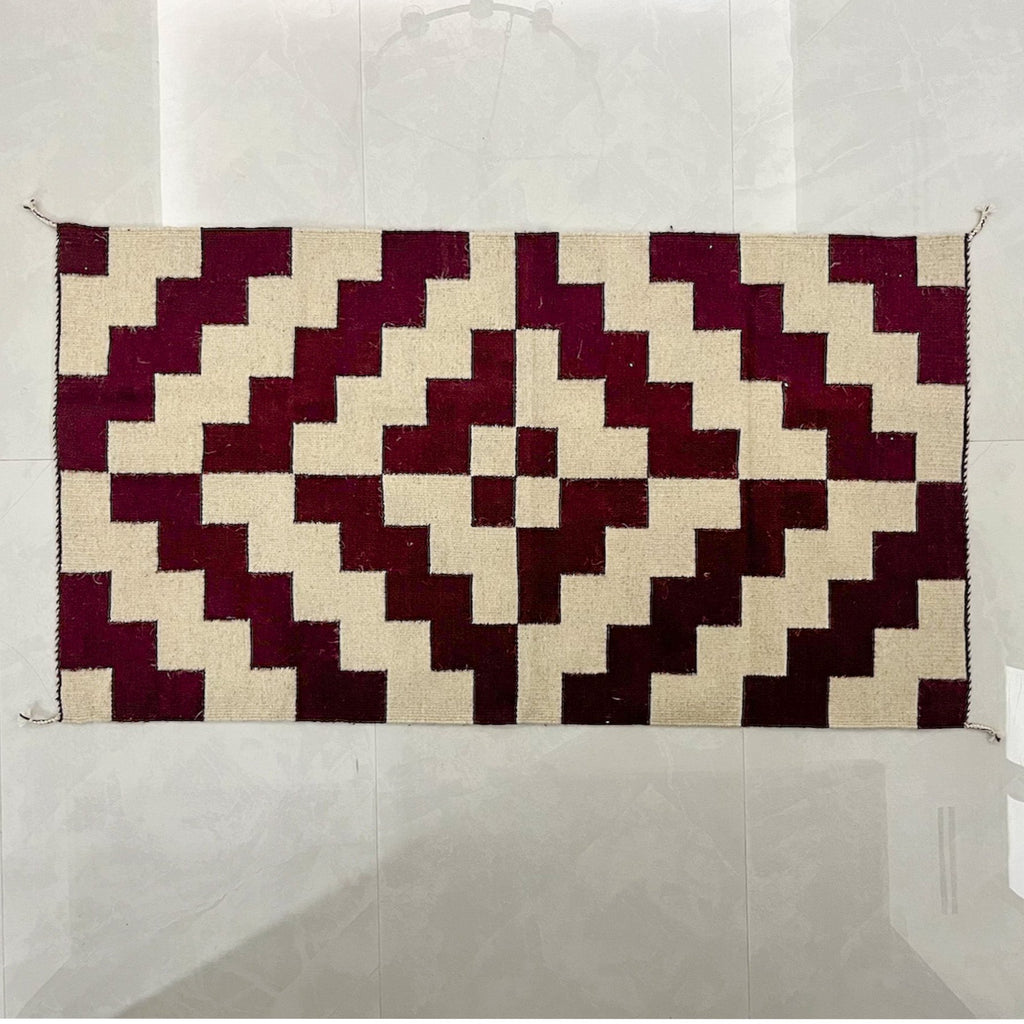 Studio CM | A maroon and cream rug with a modern geometric shape that is handwoven wool from Oaxaca Mexico