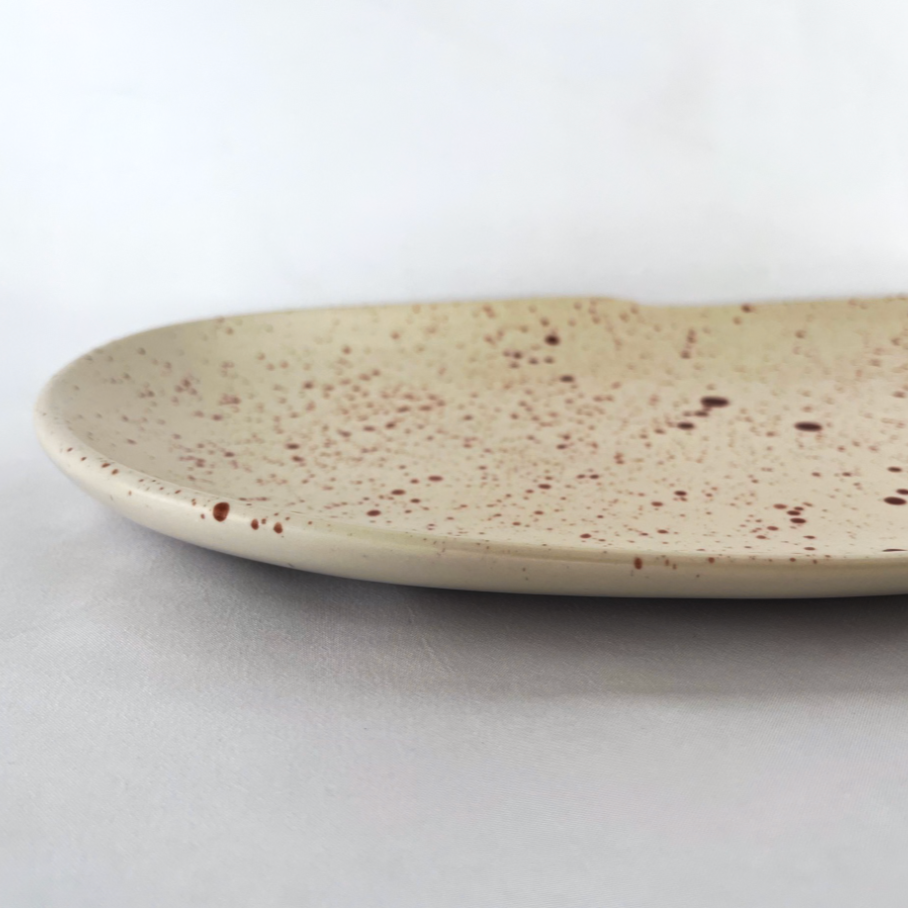 Studio CM | A long ceramic plate in a cream color with terracotta colored speckles