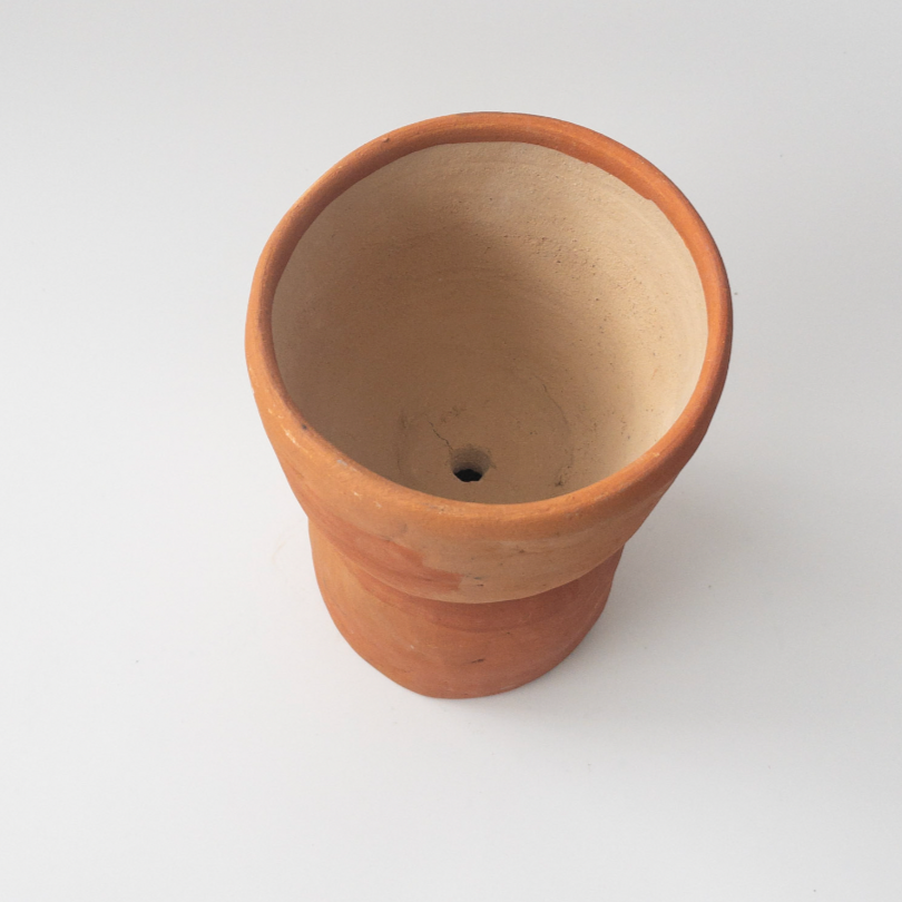 Studio CM | A terracotta colored ceramic planter that is handmade in Oaxaca with an hourglass shape with a drainage hole