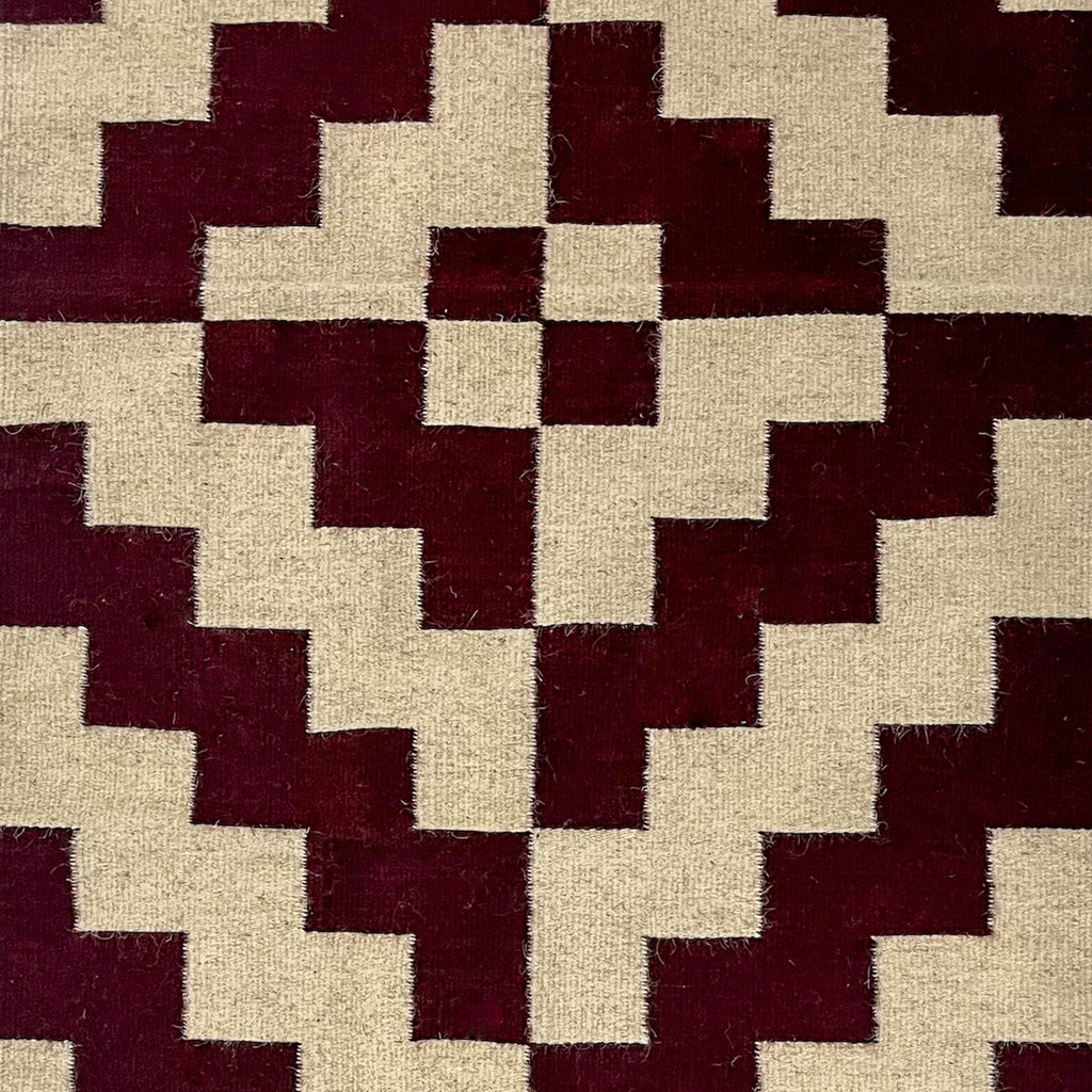 Studio CM | A maroon and cream rug with a modern geometric shape that is handwoven wool from Oaxaca Mexico