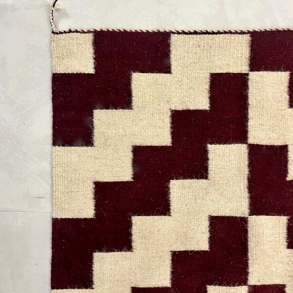 Studio CM | A maroon and cream rug with a modern geometric shape that is handwoven wool from Oaxaca Mexico