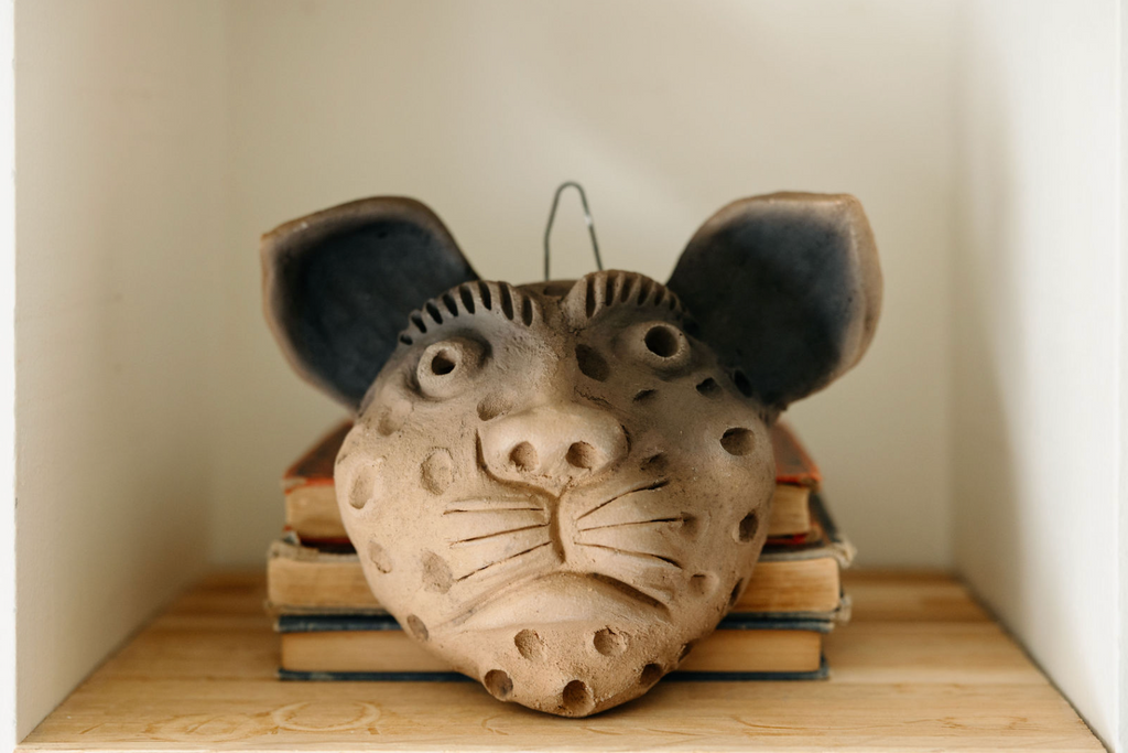 Studio CM | Ceramic jaguar head on a stack of books with a neutral background
