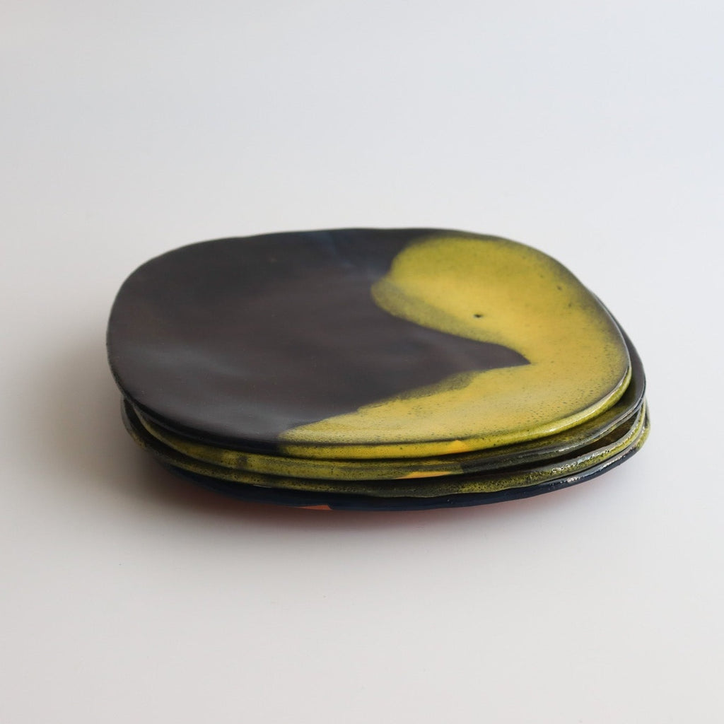 four stacked handmade ceramic plates that have blue and yellow glaze