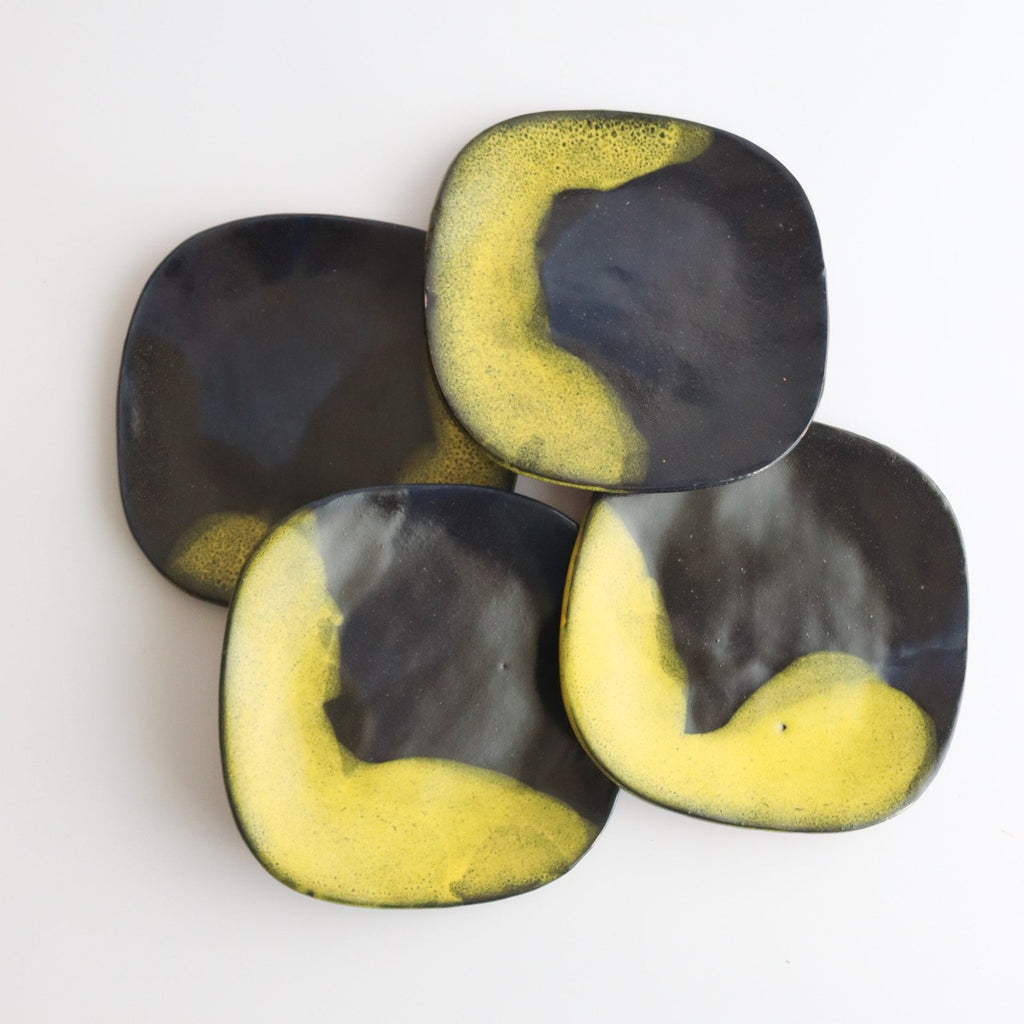 arial picture of four handmade ceramic plates that have blue and yellow glaze