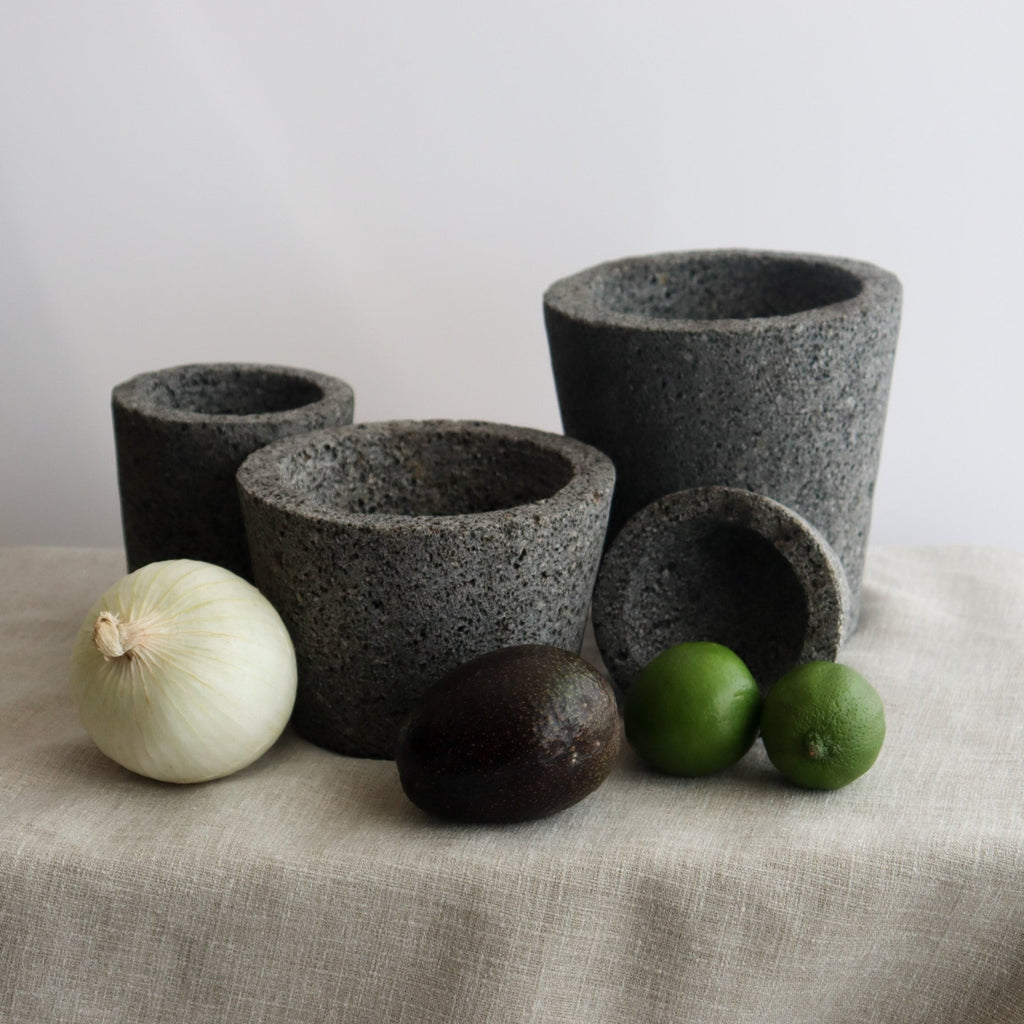 Studio CM | large volcanic stone mortar with a wooden top including a wooden pestle with a white background