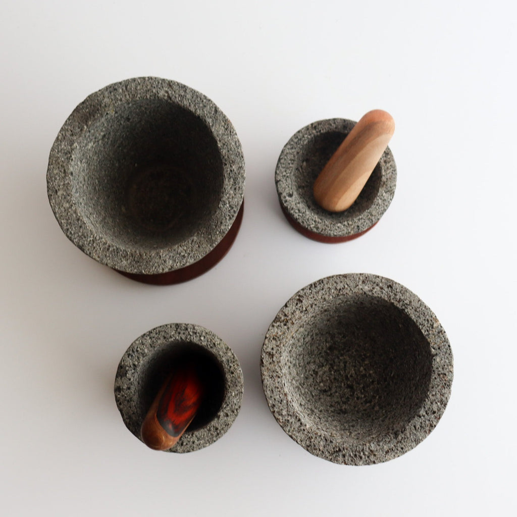 Studio CM | above view of four different sized volcanic stone mortars with two wooden pestles