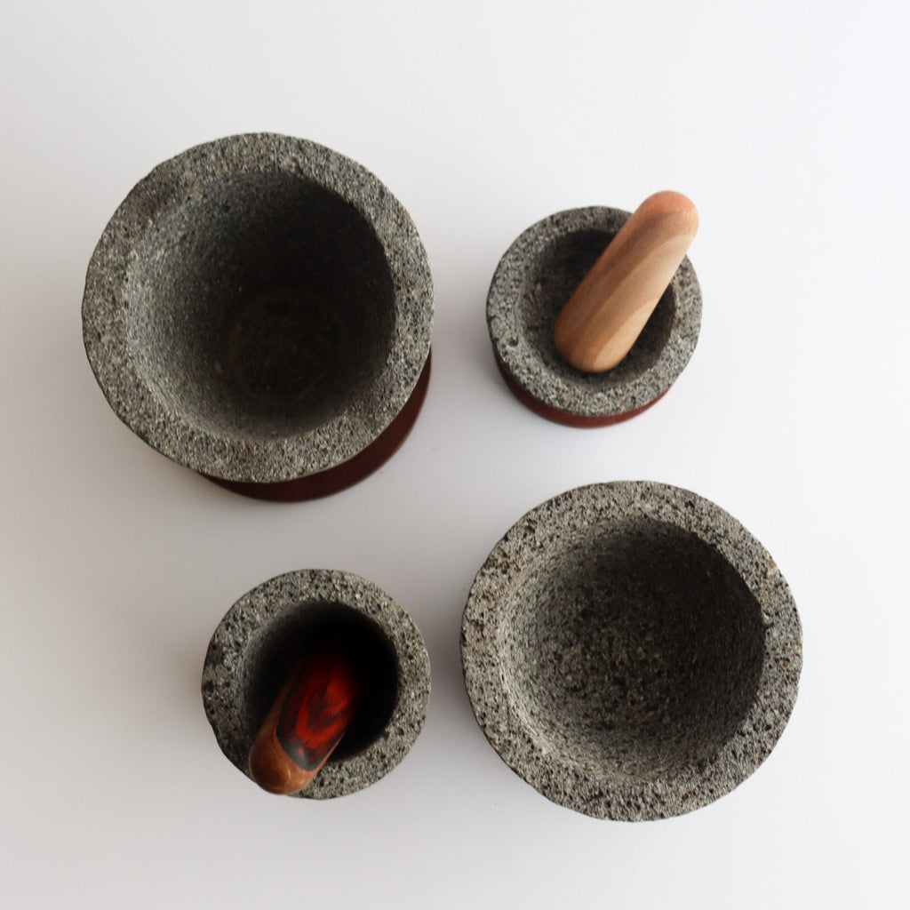 Studio CM | arial view of four sizes of volcanic stone mortars with two pestles in different sizes on a white background