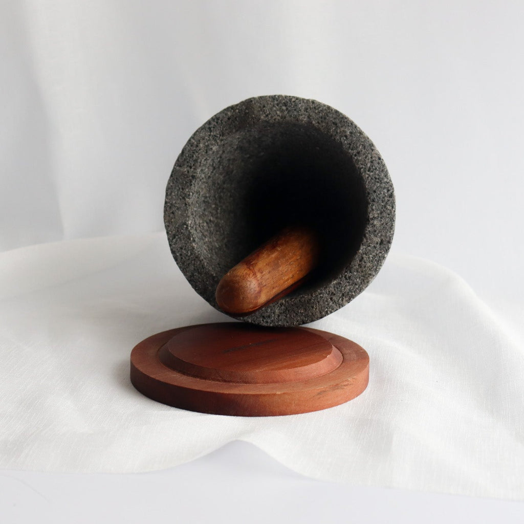 Studio CM | large volcanic stone mortar with a wooden top including a wooden pestle with a white background