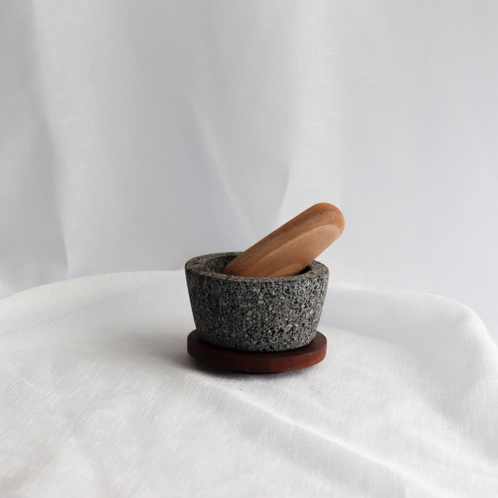 Studio CM | a small hand carved volcanic stone mortar with a wooden top and pestle