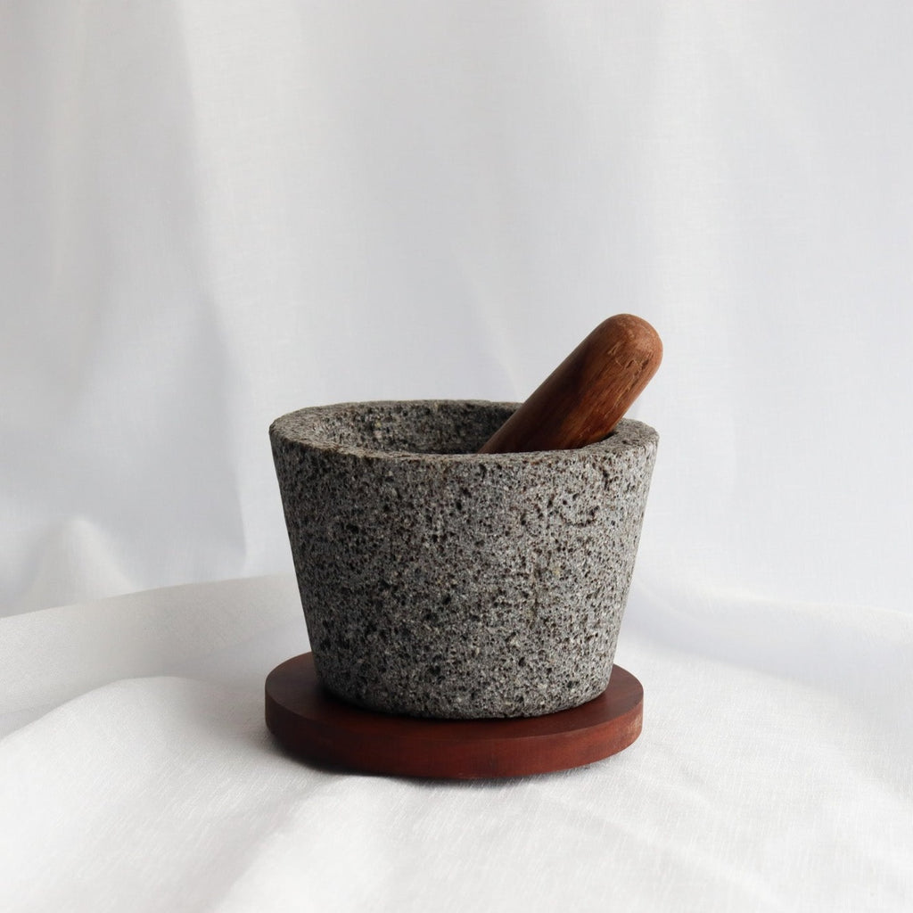 Studio CM | large volcanic stone mortar with a wooden top including a wooden pestle with a white background