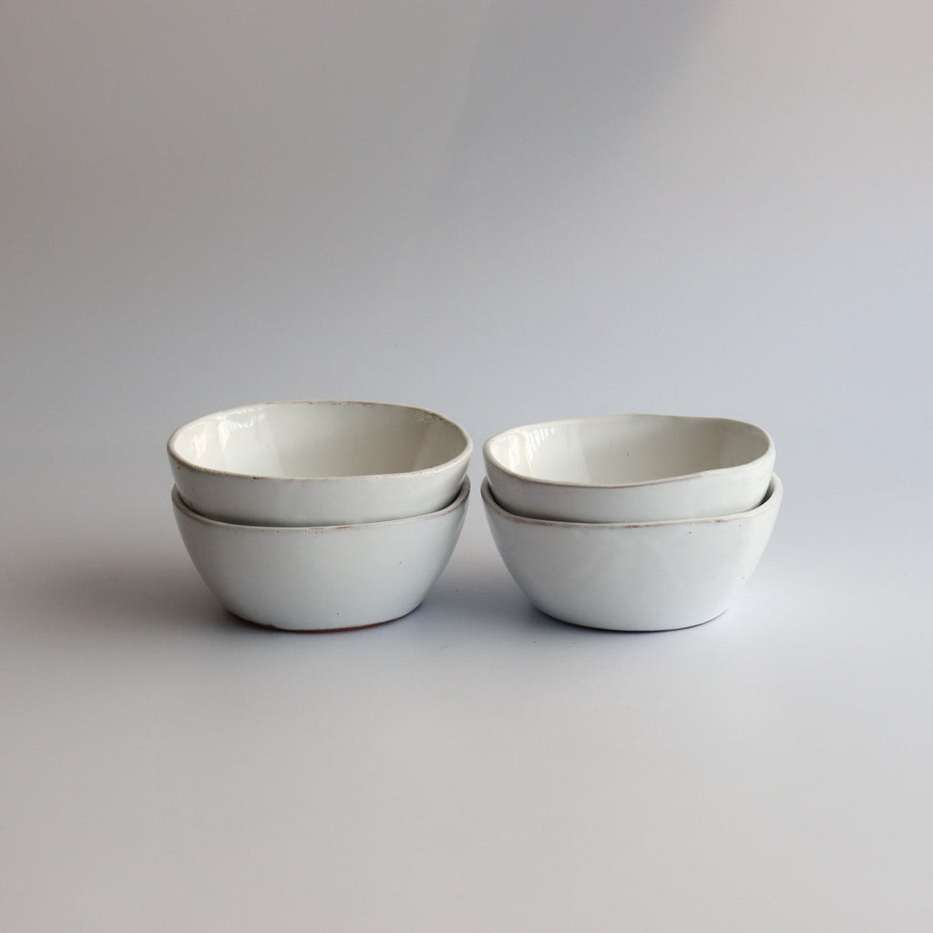 four white handmade ceramic bowls with white glaze stacked