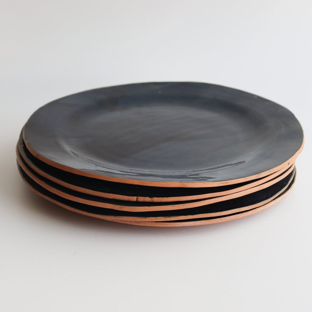 Studio CM | Ceramic plates made of clay by hand in Merida Mexico. They have an uncured bottom exposed which is terracotta color and the top is a navy blue glaze. 