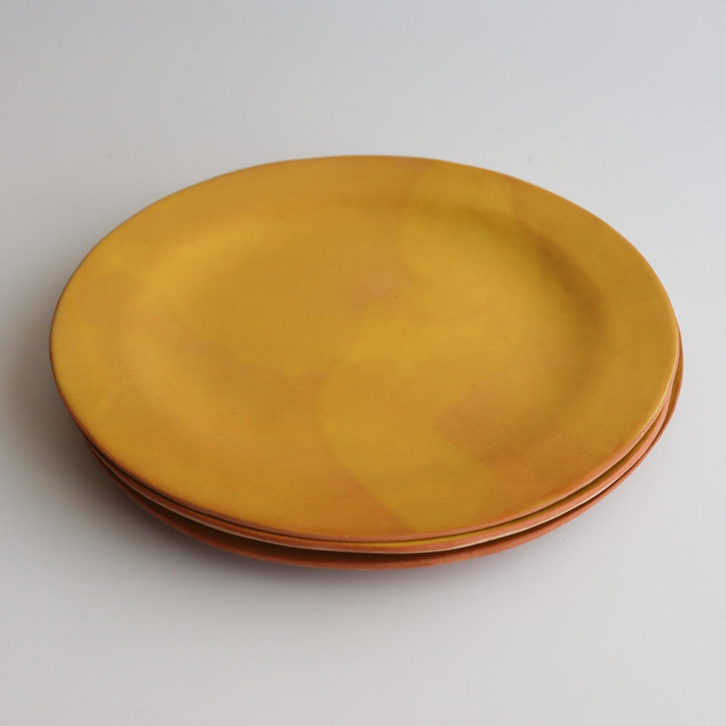 three stacked yellow ceramic plates on a white background