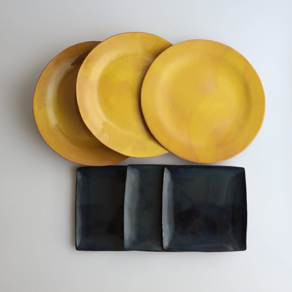 three round yellow ceramic plates and three square blue ceramic plates on a white background